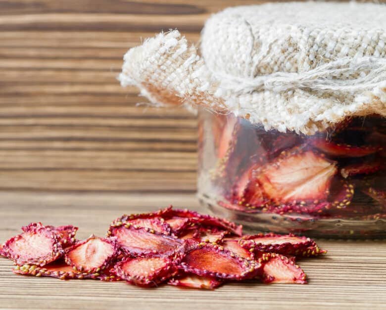 dehydrated strawberries in a jar and next to it on a wooden background