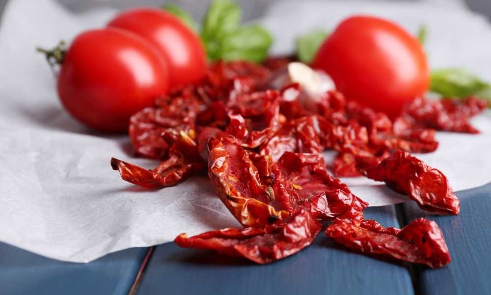 sun dried tomatoes next to whole tomatoes on paper