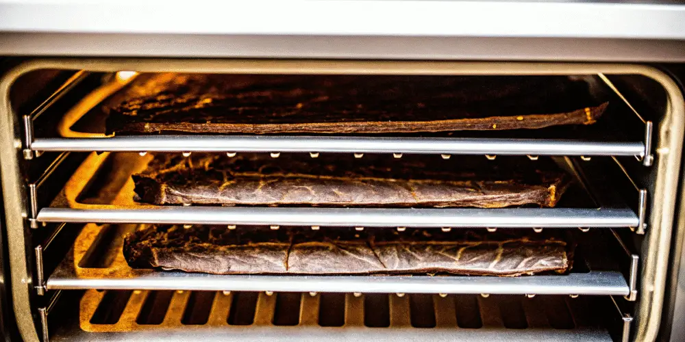 Beef jerky slices in a food dehydrator tray.