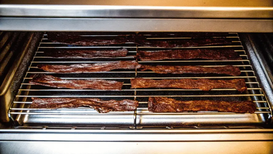 Beef jerky strips on a steel tray.