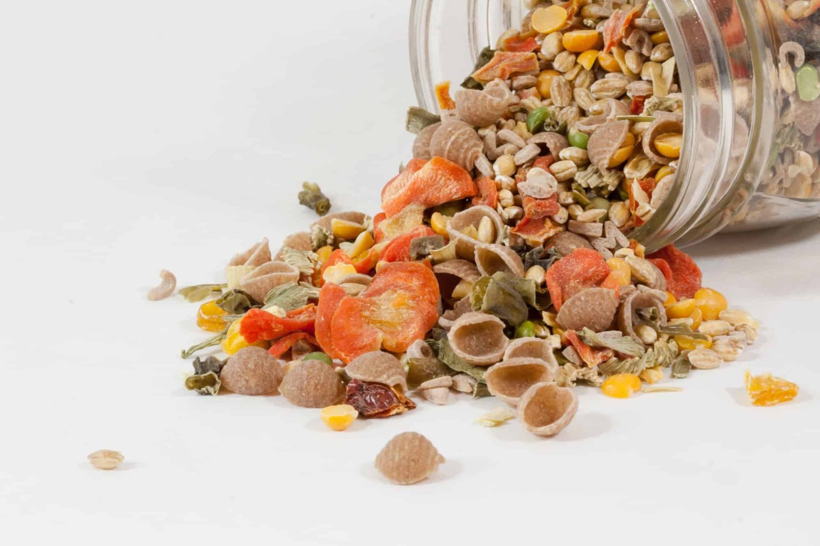 assortment of dried food in a jar tipped over on a white background