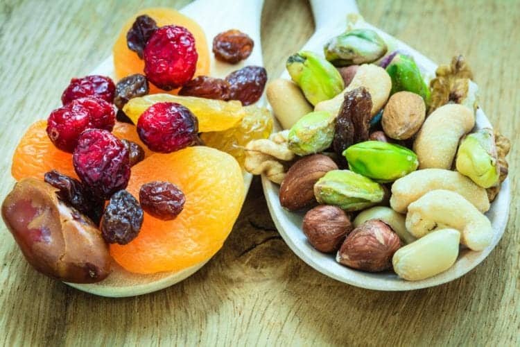 Healthy food organic nutrition. Closeup different varieties mix of dried fruits and nuts on wooden spoons.
