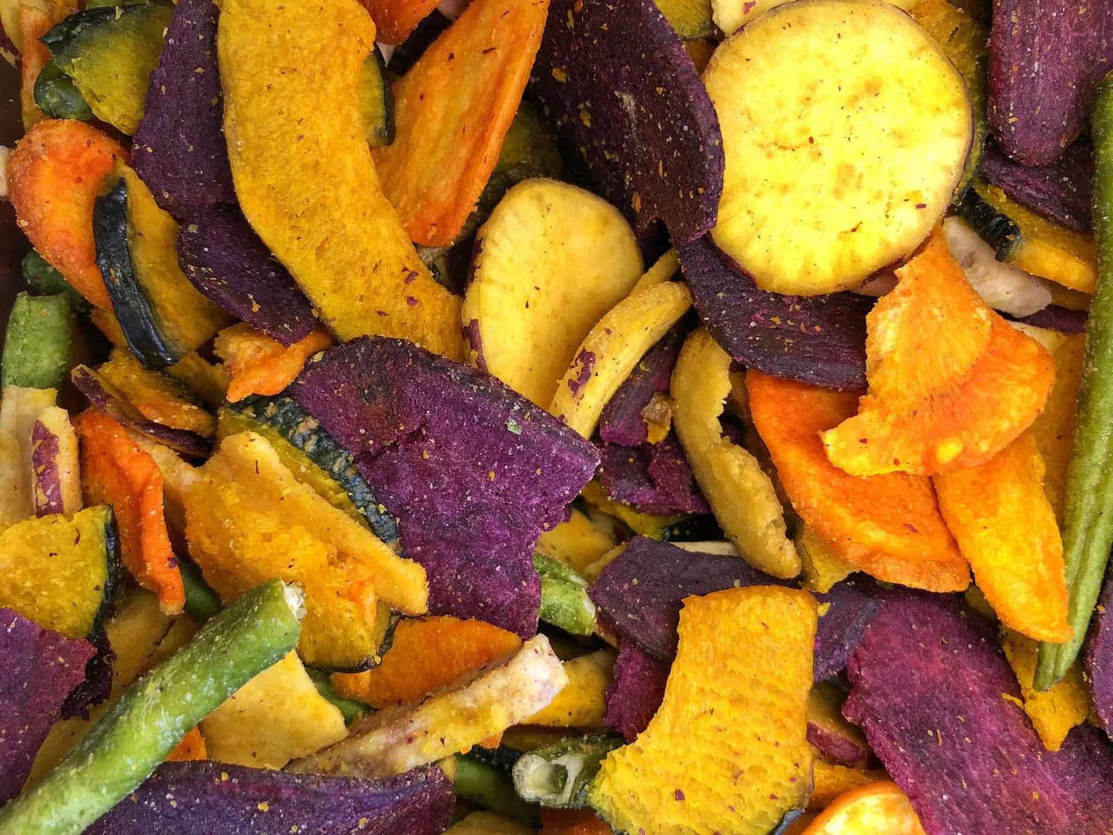 Food background veggie chips. Yellow sweet potatos, purple sweet potato, squash, taro, carrots and green beans.