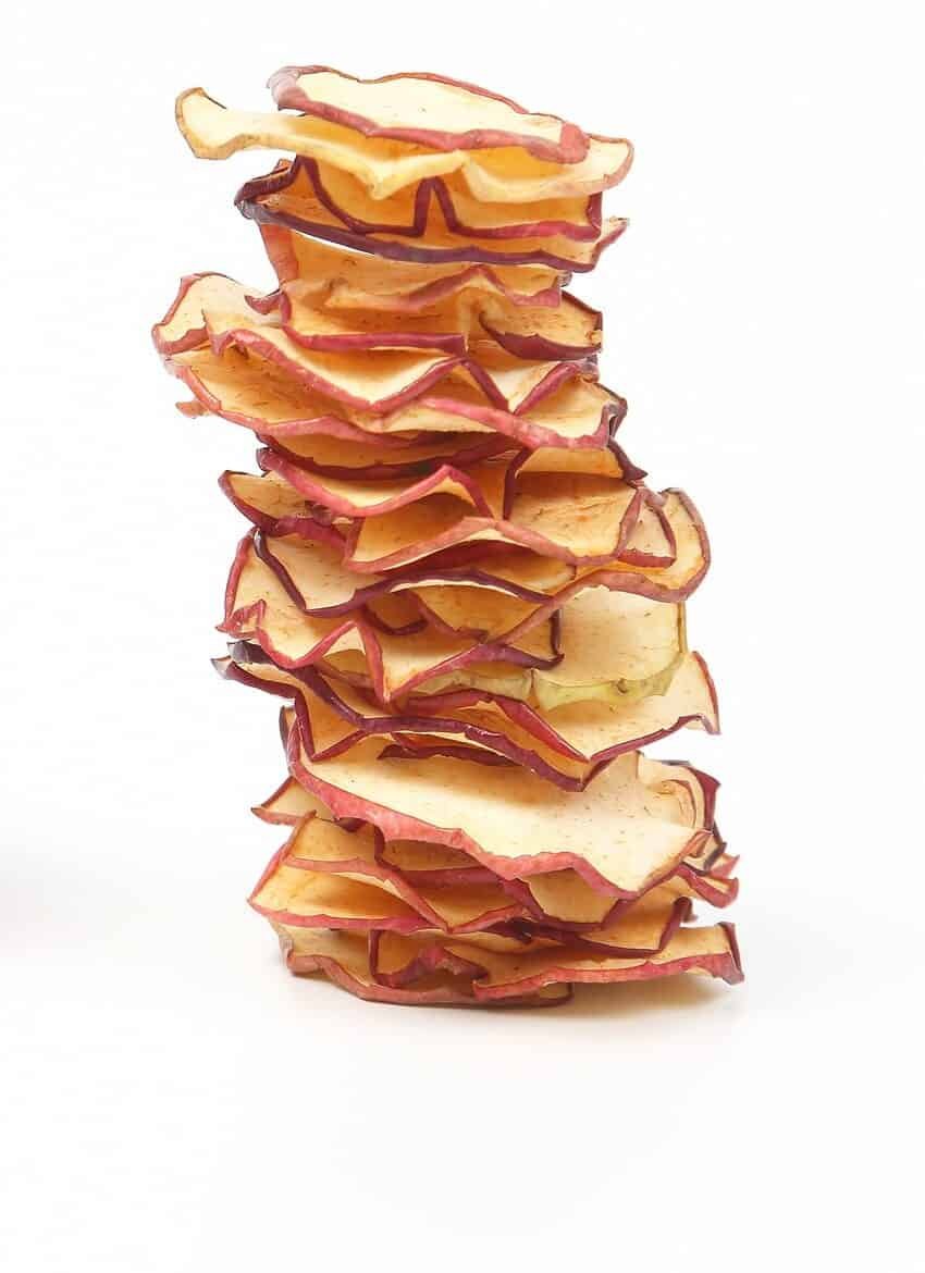 Fresh Apple and a stack of dried Apple slices on white background