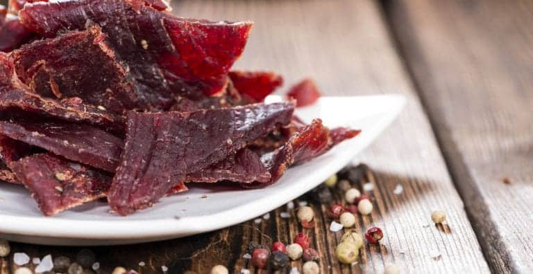 beef jerky on white plate with wooden table