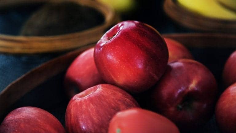 red shiny apples in wooden brown bowl