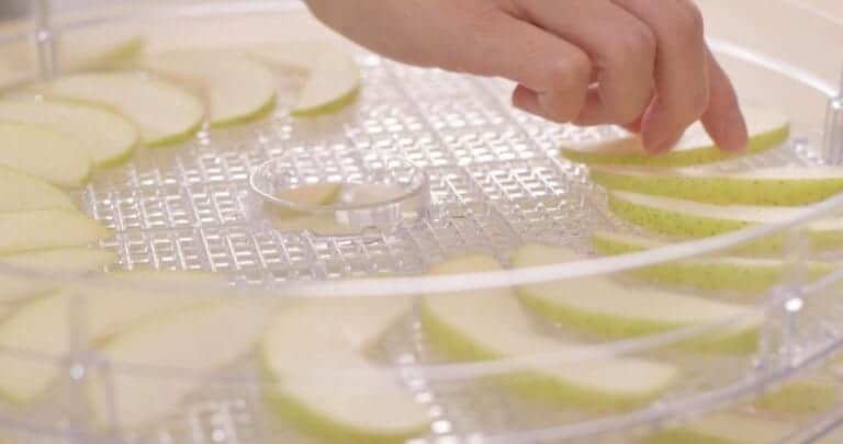 sliced pears being put in cylinder dehydrator tray