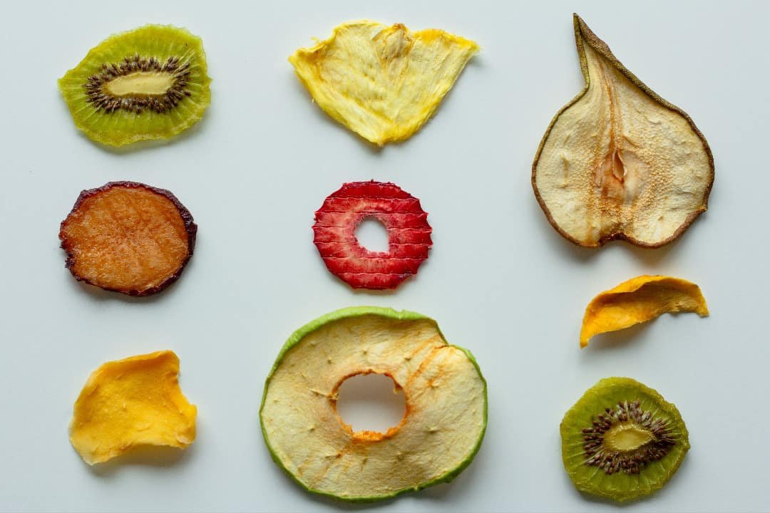 different sliced fruits dehydrated on light grey backdrop