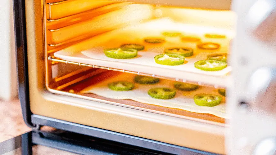 A digital food dehydrator in action, with the temperature set to 125°F. The trays inside are visible, filled with jalapeno slices.