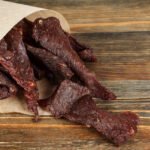 beef jerkyy in paper bag on wooden background