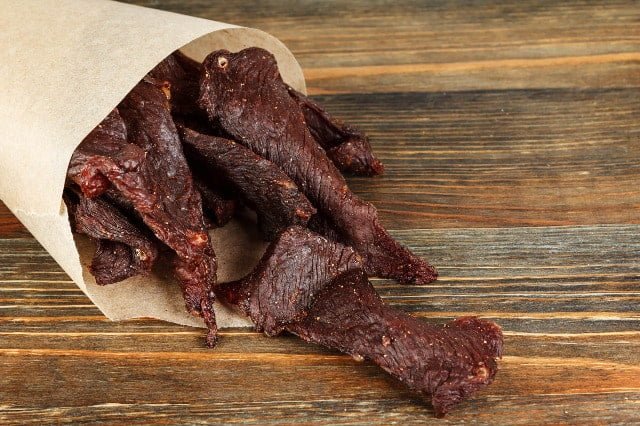 beef jerkyy in paper bag on wooden background