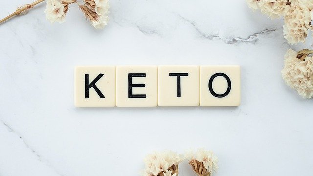 the word keto on a mwhite marble background with white flowers around image