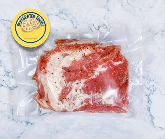 vacuum sealed beef in bag on stone worktop . Dehydratedfoodz Logo yellow on top left.