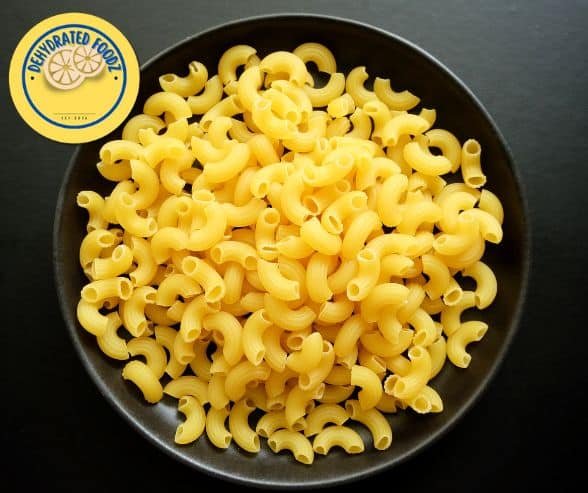 Macaroni pasta in a black bowl on a grey background