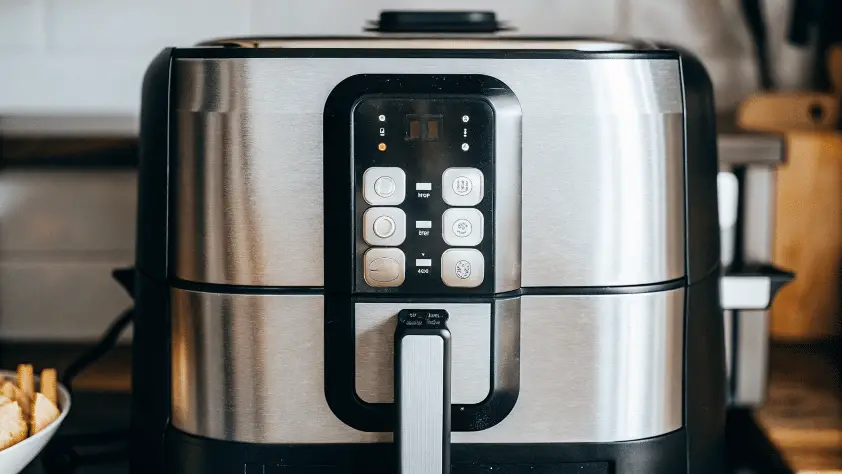 A sleek silver air fryer on a kitchen table