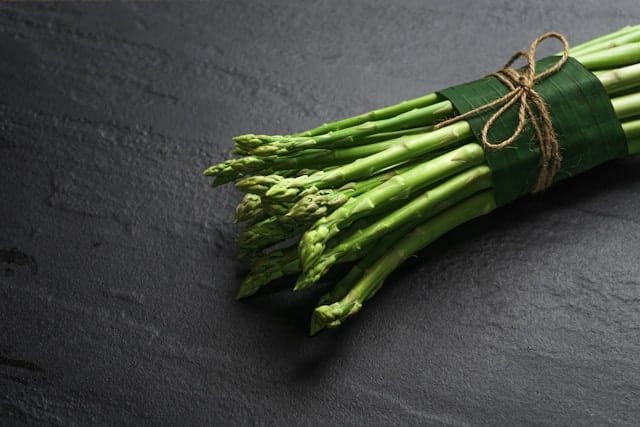 a bunch of asparagus on a grey background.