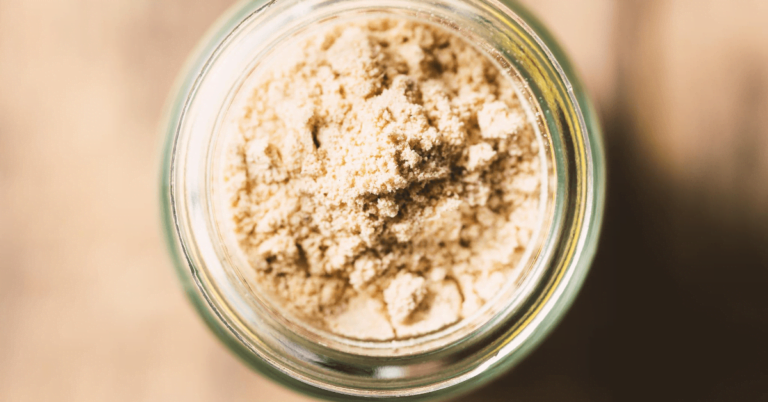 powdered peanut butter in a glass jar on a wooden background.