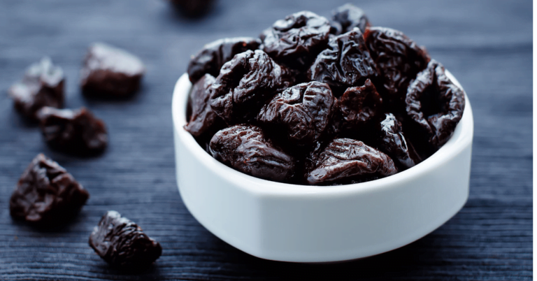 Prunes in a white bowl on a dark grey table