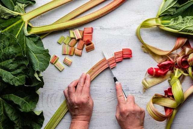 rhubarb being cut by person on a grey table