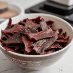 a bowl full of beef jerky on a kitchen countertop