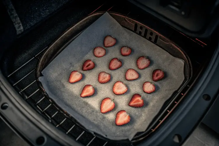 strawberry slices in a single layer on the parchment paper lined air fryer basket