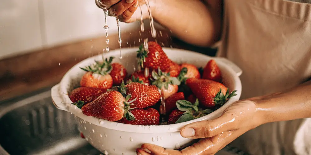 fresh strawberries being washed in a bowl.