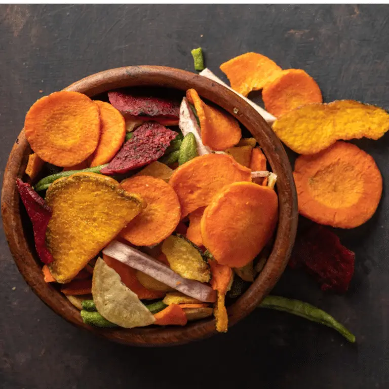 dehydrated vegetable chips in a bowl on a dark grey background.