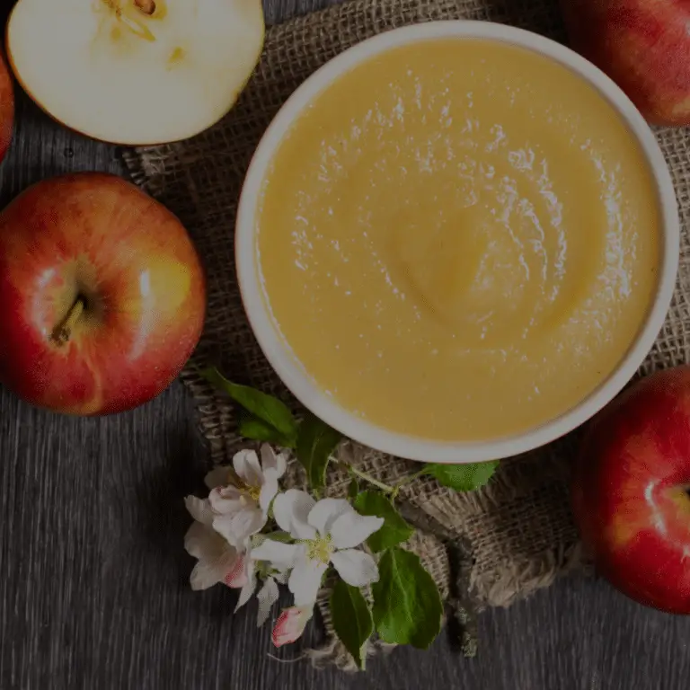 applesauce surrounded by red apples on a wooden background