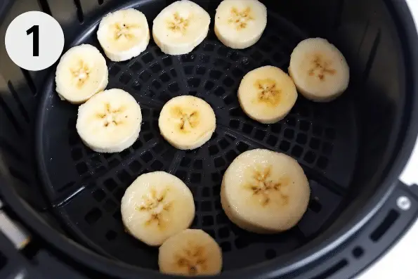 Sliced banana slices in an air fryer basket.