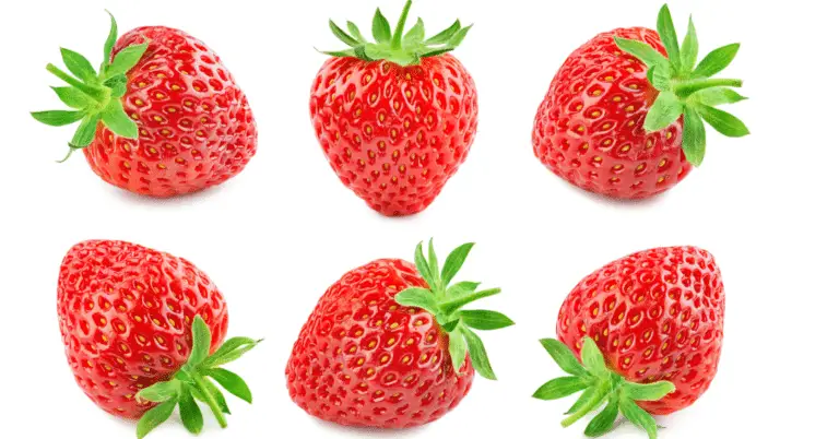 six strawberries with tops on a white background