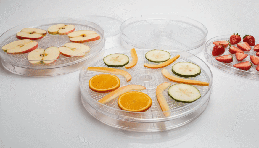 The image features several dehydrator trays stacked together, showcasing their non-stick surface designed for easy cleanup during the dehydration process. These trays can be lined with parchment paper or silicone sheets to prevent sticking while drying fruits, vegetables, and meats, ultimately extending their shelf life.