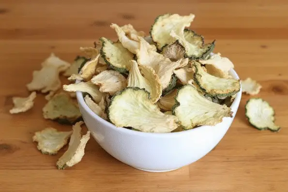 Dehydrated cucumber chips in a white bowl.