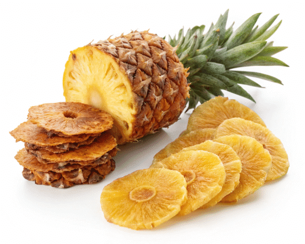A fresh pineapple next to stacks of dried pineapple slices on a white background.