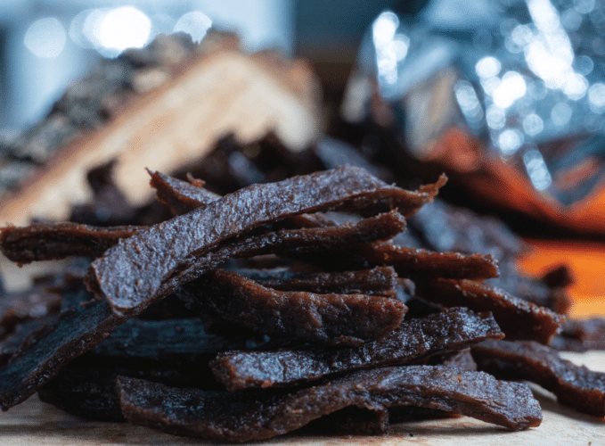 Pile of dark chocolate bark pieces dusted with sugar on a wooden board