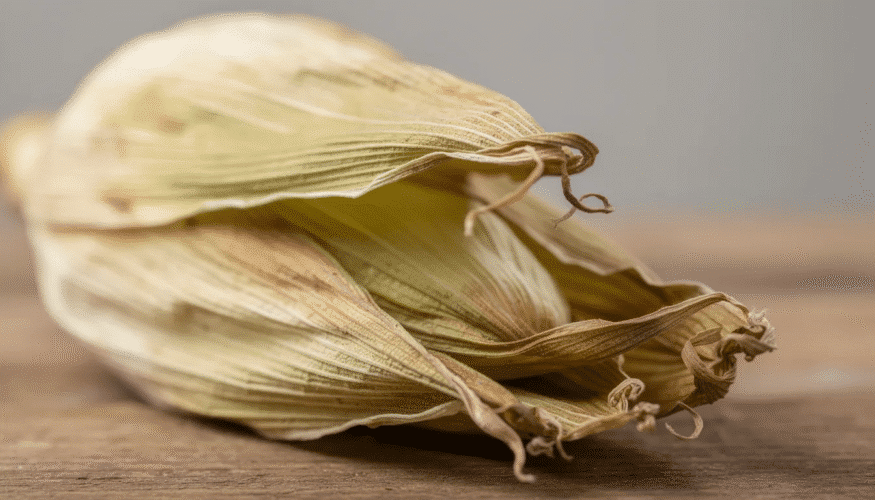 The image features a collection of dried corn husks arranged in a basket, showcasing their crisp texture and natural color. This visual represents the drying process of corn husks, which can be preserved for use in easy DIY projects or as a craft material.