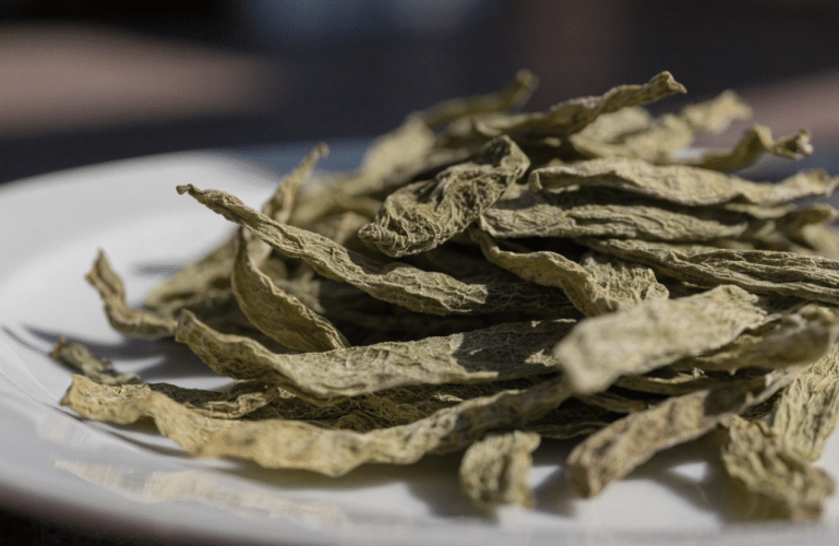 Pile of dried, wrinkled leaf-like chips resting on a white plate.