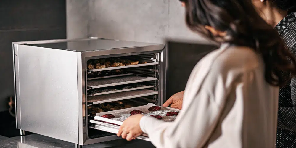 A 12 tray sleek food dehydrator with food in the trays.