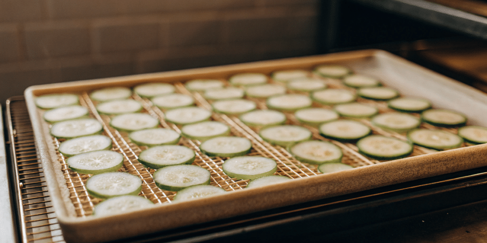 sliced cucumber in a food dehydrator tray.