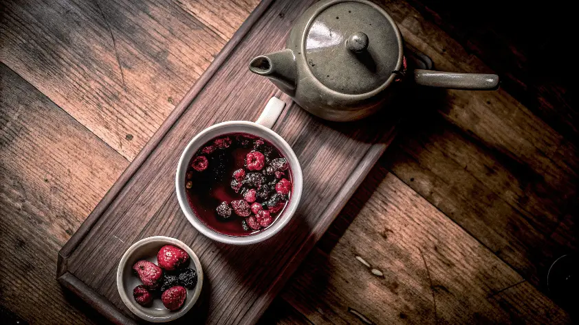 Berry tea in a cup on a wooden table.